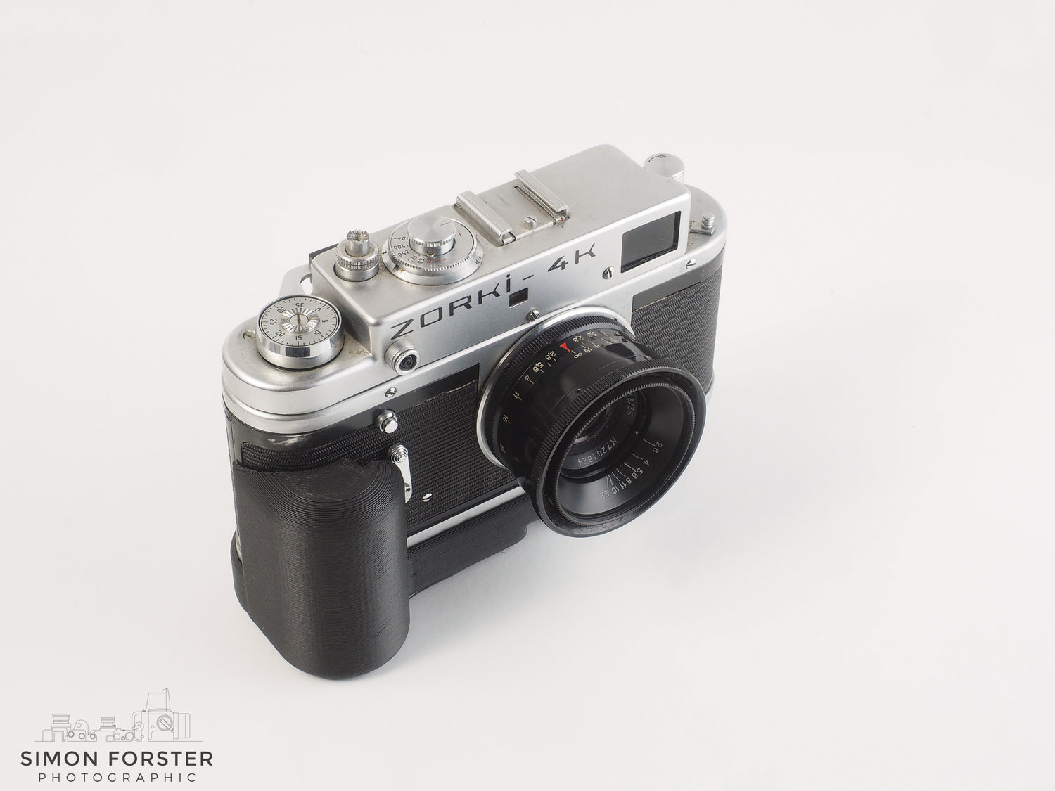 A Zorki 4K camera with a black grip attached to it, set against a white background.