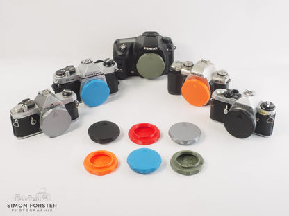 Assorted PK mount body caps caps in various colours for Pentax K mount cameras by Forster UK a on white background.