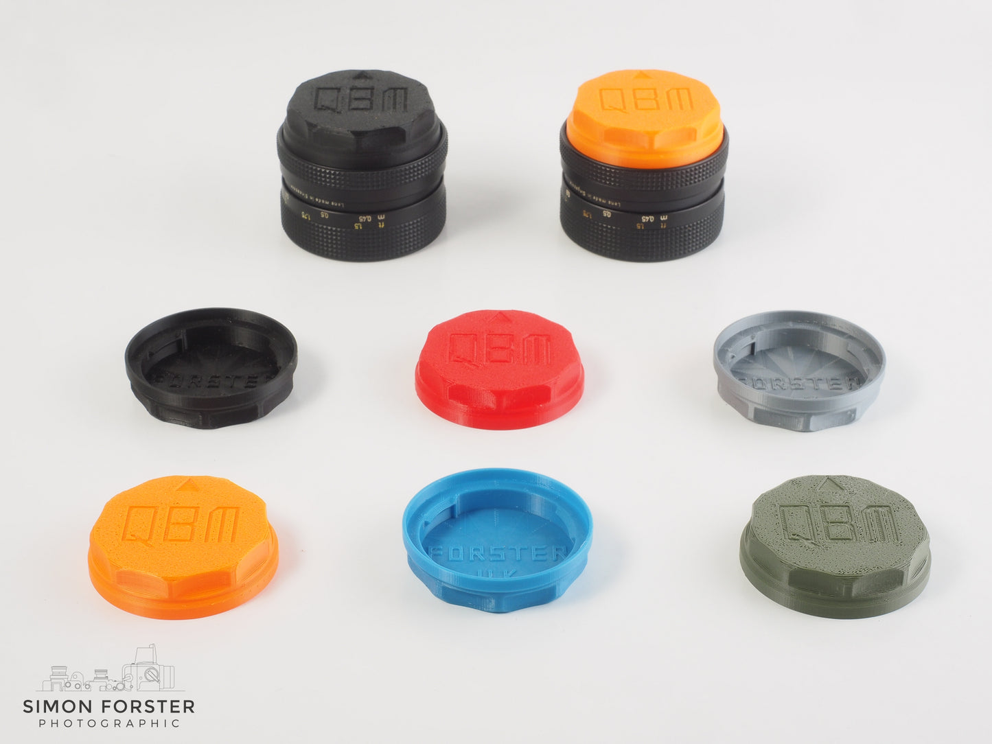 A selection of six different colour variations of the same Rollei QBM rear lens caps, the colours consist of black, orange, red, light blue, silver and military green. The caps are being showcase in a professional white background.