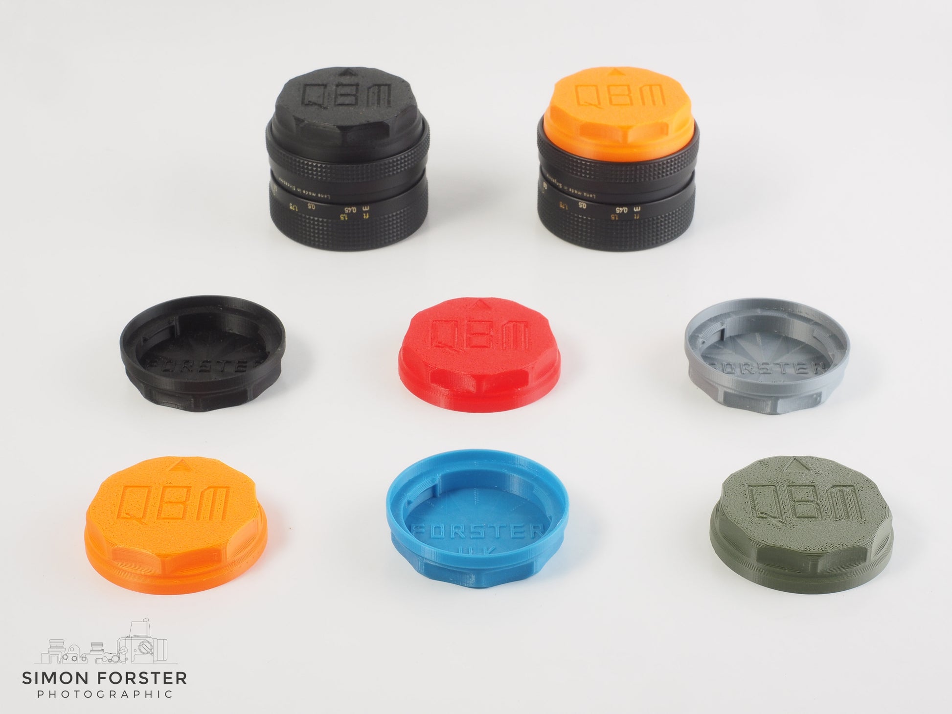 A selection of six different colour variations of the same Rollei QBM rear lens caps, the colours consist of black, orange, red, light blue, silver and military green. The caps are being showcase in a professional white background.