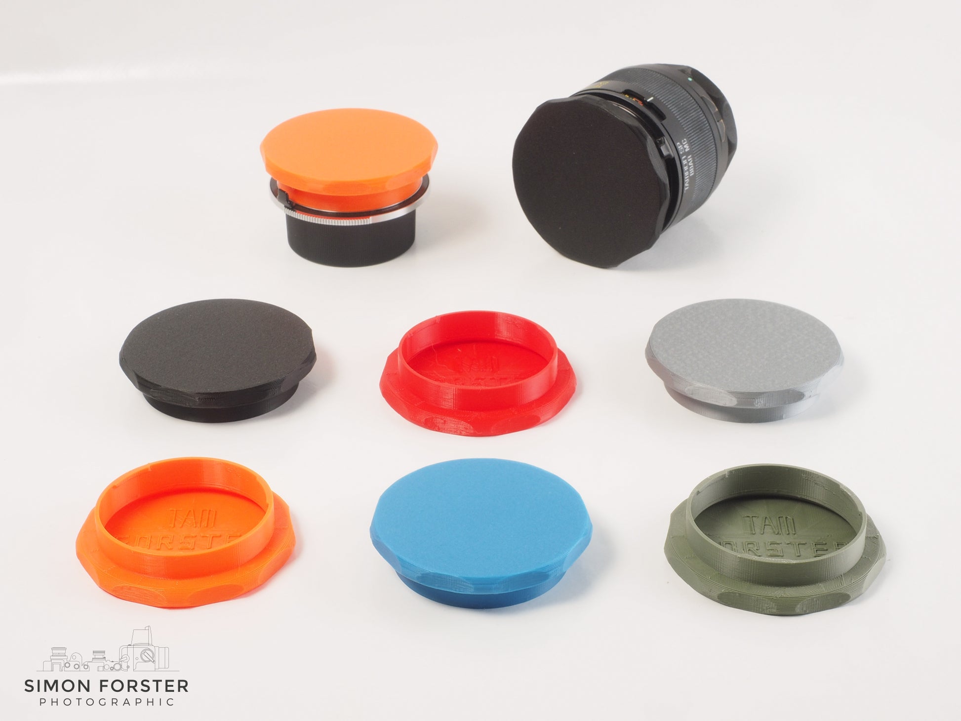 Assorted Forster UK TAMRON adaptall and adaptall2 mount front caps in various colours on a white backdrop.