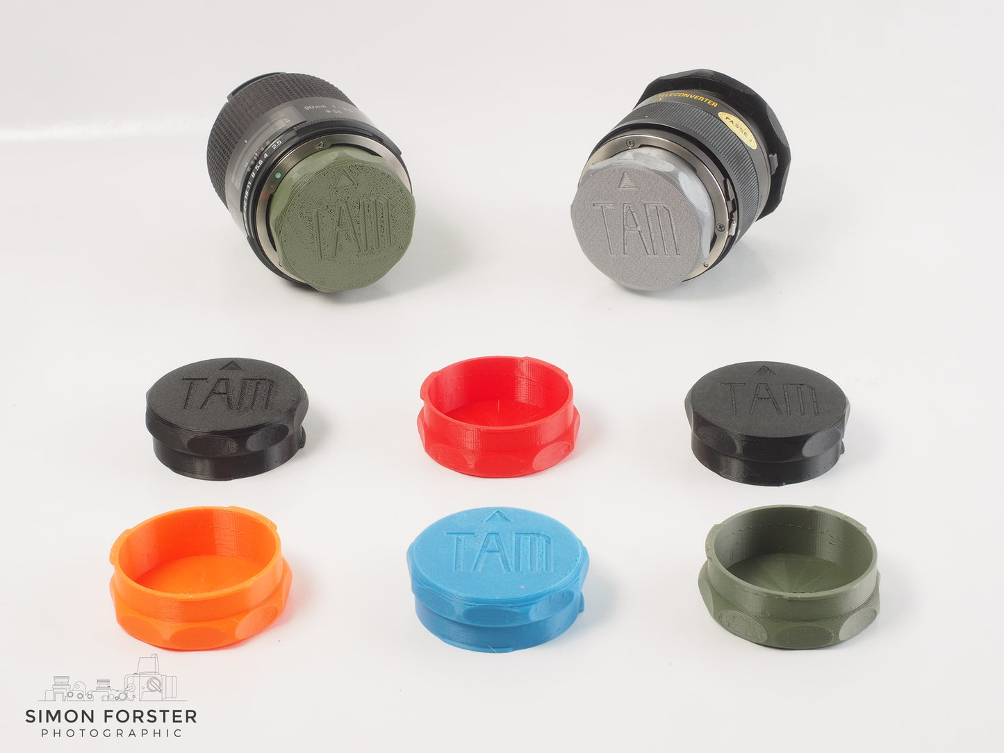 Assorted Forster UK TAMRON adaptall and adaptall2 mount rear lens caps in various colours on a white backdrop.